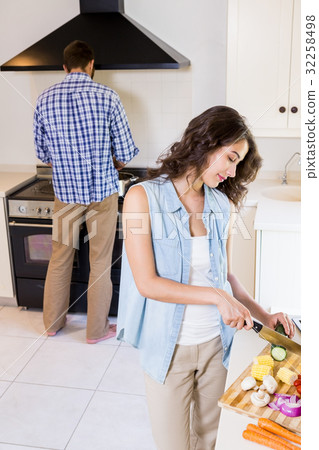 Woman chopping vegetables and man cooking on stove Woman chopping vegetables and man cooking on stove 32258498