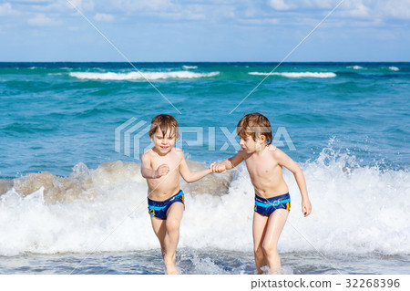 Two kid boys running on ocean beach in Florida 32268396