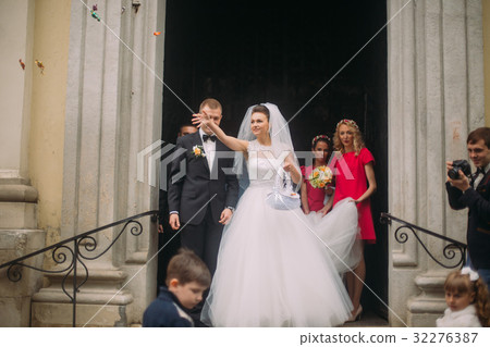 The bride is throwing the candies near the church. 32276387