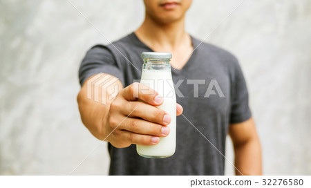 Man holding a bottle of milk on gray background. 32276580