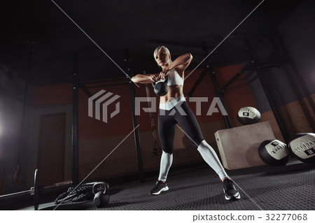 Muscular young fitness woman lifting a weight in 32277068