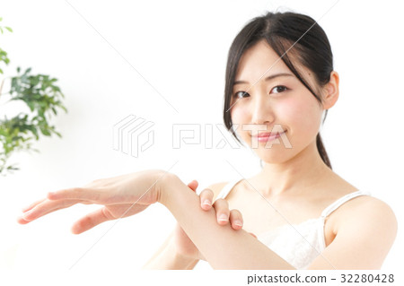 A young Japanese woman applying a cream 32280428