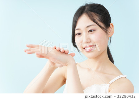 A young Japanese woman applying a cream 32280432