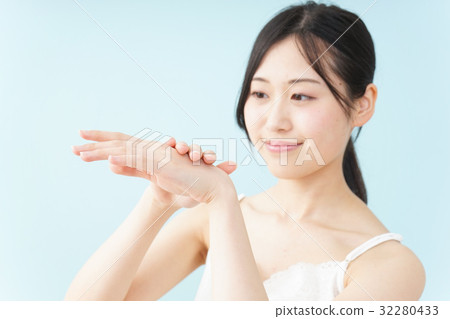 A young Japanese woman applying a cream 32280433