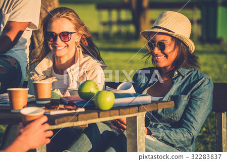 Multi-ethnic friends drinking coffee and chatting Multi-ethnic friends drinking coffee and chatting 32283837