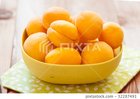 Heap of apricots in wooden bowl on table Heap of apricots in wooden bowl on table 32287491