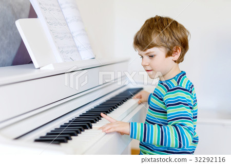 Beautiful little kid boy playing piano in living Beautiful little kid boy playing piano in living 32292116