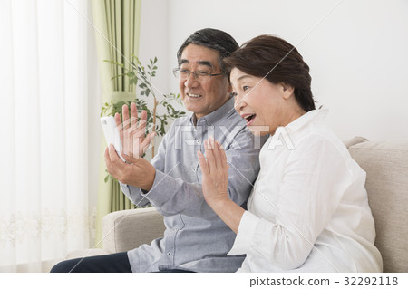 A senior couple who makes a TV phone with a smartphone to a grandchild who is away A senior couple who makes a TV phone with a smartphone to a grandchild who is away 32292118