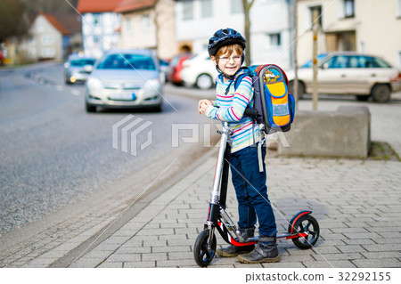 Little kid boy in helmet riding with his scooter Little kid boy in helmet riding with his scooter 32292155