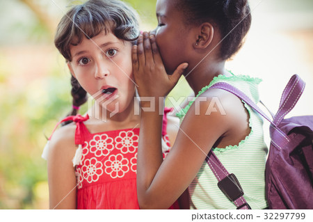 Girl telling a secret to her friend 32297799