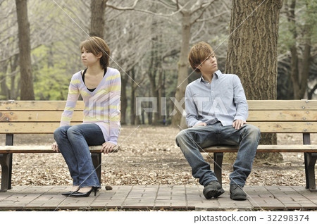 A couple sitting on the bench and facing a tail 32298374