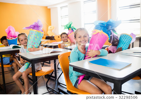happy pupils sitting at their desk with gifts boxes 32298506
