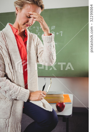 Sad teacher sitting on desk 32299864