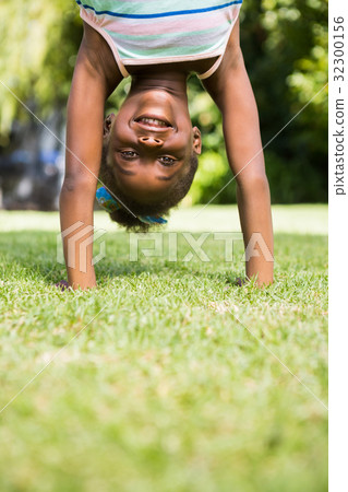 Portrait of a cute mixed-race girl smiling and doing a headstand 32300156