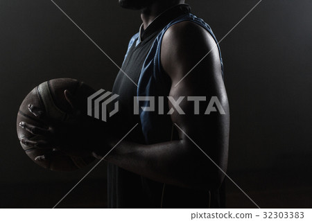 Zoom on a side of a basketball player holding a basketball Zoom on a side of a basketball player holding a basketball 32303383