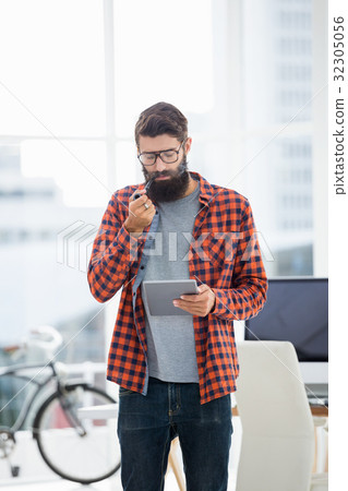 Hipster using tablet while standing Hipster using tablet while standing 32305056
