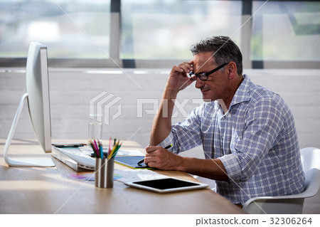 Side view of a businessman working at desk Side view of a businessman working at desk 32306264
