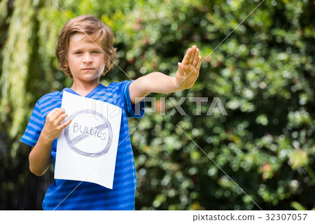 Serious boy saying stop with his hand and holding a message Serious boy saying stop with his hand and holding a message 32307057