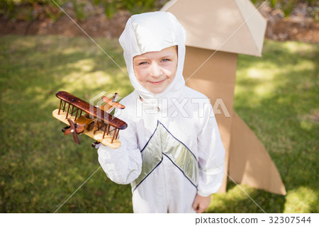 Portrait of cute boy with astronaut dress holding a little plane Portrait of cute boy with astronaut dress holding a little plane 32307544