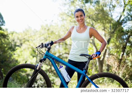 Woman smiling and posing with her bike Woman smiling and posing with her bike 32307717