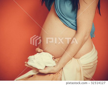 pregnant woman with small shoes for unborn baby 32314127