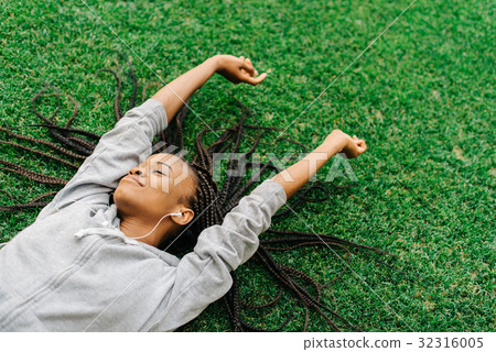 Delighted afro-american teenager is enjoying music Delighted afro-american teenager is enjoying music 32316005