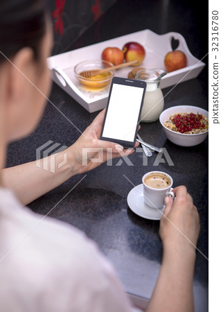 woman having breakfast while using smartphone 32316780