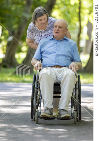Senior woman pushing husband in wheelchair Senior woman pushing husband in wheelchair 32316781