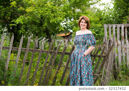 woman in long dress near an old fence in village woman in long dress near an old fence in village 32317432