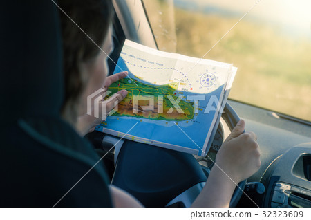 A young woman is driving a car looking at the map A young woman is driving a car looking at the map 32323609