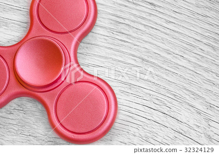 Red fidget spinner on background white wood.  32324129