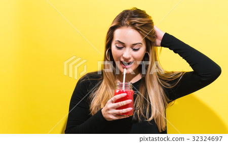 Happy young woman drinking smoothie Happy young woman drinking smoothie 32324697