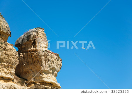 eroded sandstone cliff and seagull in blue sky 32325335