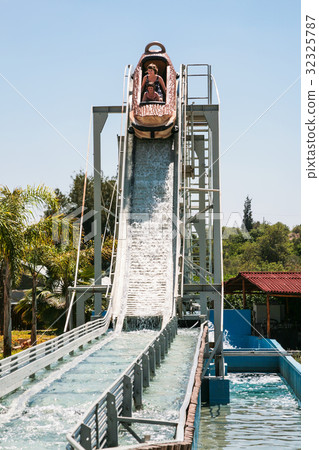 riders in boat on water slide attraction 32325787