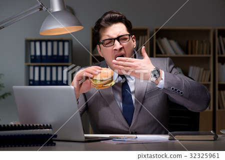 Businessman late at night eating a burger Businessman late at night eating a burger 32325961