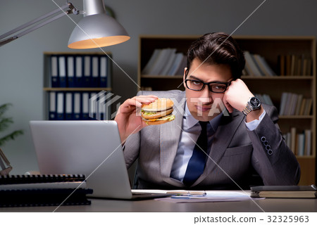 Businessman late at night eating a burger Businessman late at night eating a burger 32325963