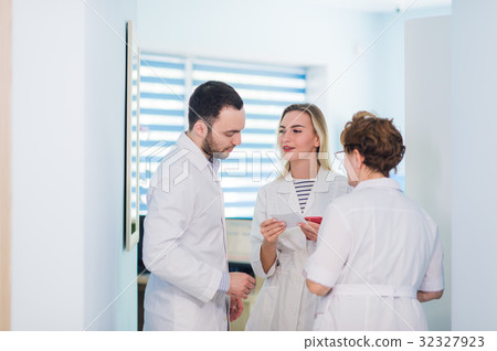 Mature doctor discussing with nurses in a hallway 32327923