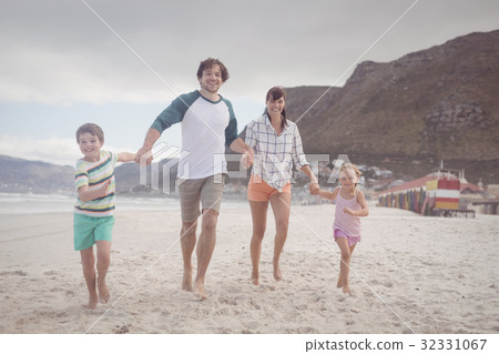 Portrait of family holding hands on sand at beach Portrait of family holding hands on sand at beach 32331067
