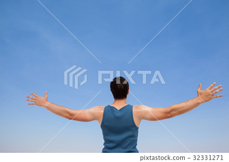 Man standing at beach with arms outstretched 32331271