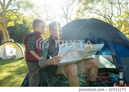 Father and son looking at map outside the tent 32331275