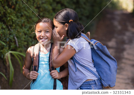 Girl whispering to smiling friend natural parkland Girl whispering to smiling friend natural parkland 32331343