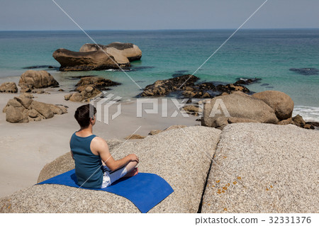 Man performing yoga on rock 32331376