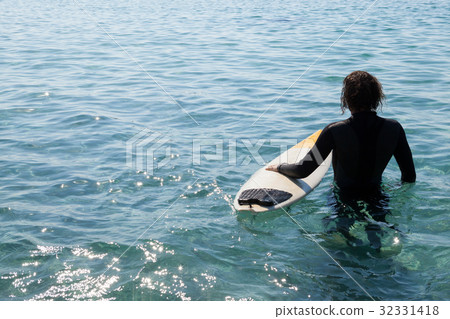 Surfer with surfboard standing in sea 32331418