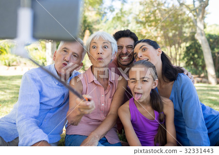 Family making funny faces while taking a selfie in the park Family making funny faces while taking a selfie in the park 32331443