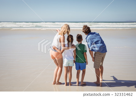 Rear view of family standing together at beach 32331462