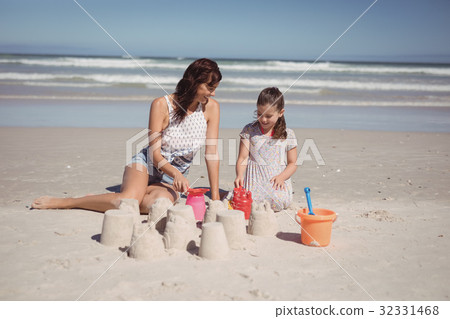 Happy girl with mother making sand castle at beach 32331468