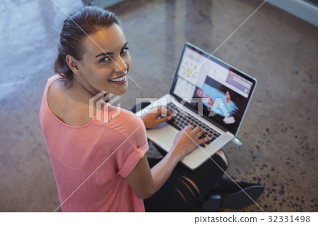 Portrait of graphic designer working on laptop while sitting at floor 32331498