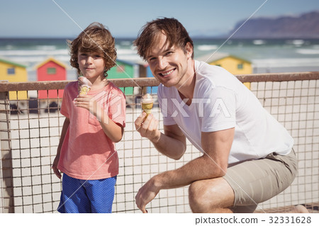 Portrait of father with son eating ice cream by railing 32331628