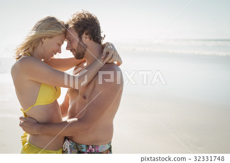 Side view of young couple embracing at beach 32331748