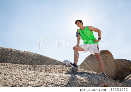 Exhausted man taking a break after jogging on beach 32331952